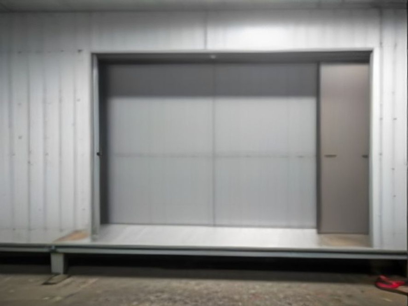 Flush modern steel garage door and matching side door on a light industrial facade